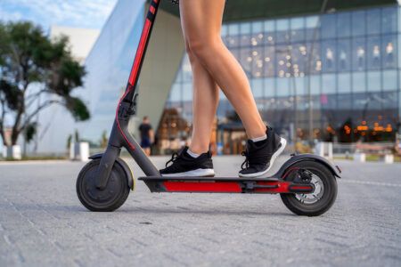 Closeup shot girls legs in sneakers on Electric push scooter