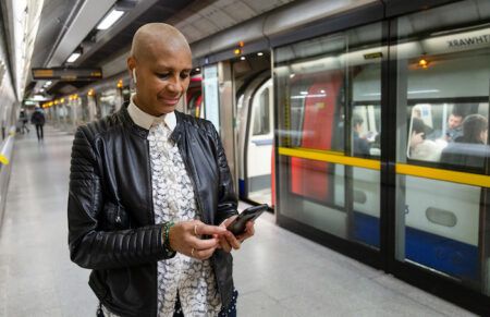 A woman uses her smartphone on a Jubilee line Underground platform, part of the London Underground subway system