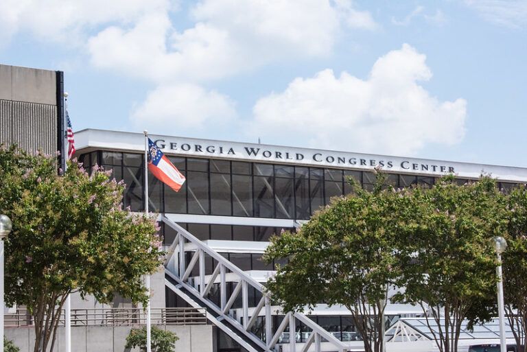 Picture of the exterior of congress center with blue sky and Georgia State flag flying