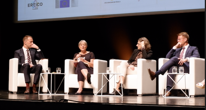 Speakers sit on a stage at a round table congress event