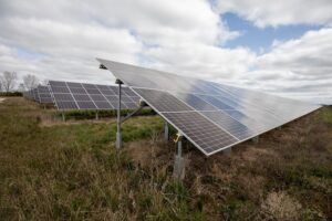 Solar panels in a field on a sunny day with some clouds