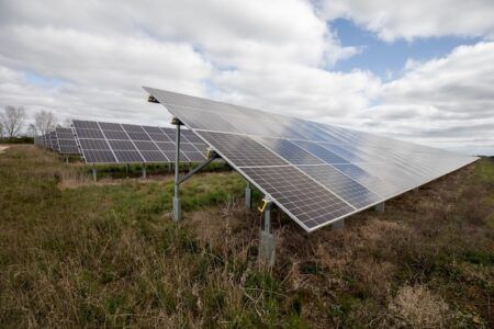 Solar panels in a field on a sunny day with some clouds