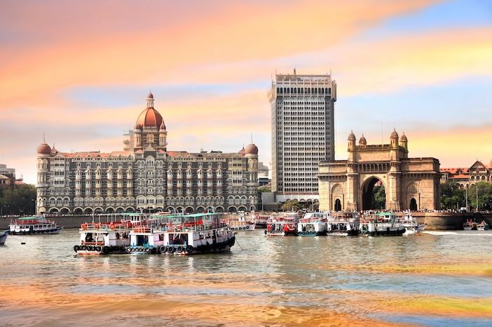 River in Mumbai with old ferries and showing the  Gateway of India, a basalt arch