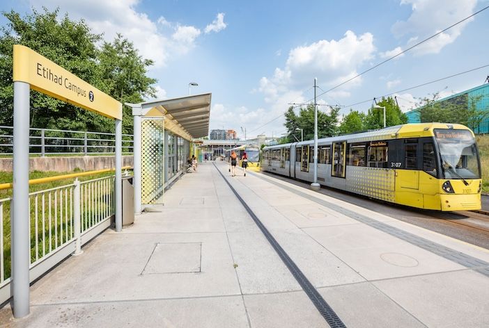 A tram stop in Manchester with yellow tram