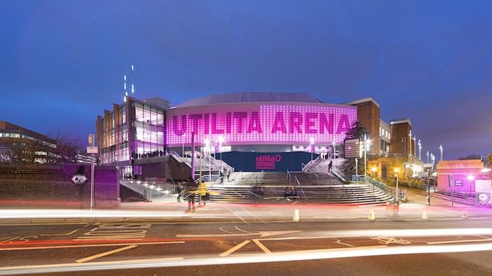 A modern arena building lit up at night