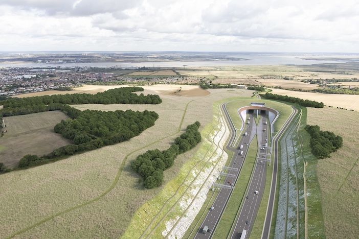 Aerial view of a dual carriageway road with embankments on either side entering a tunnel