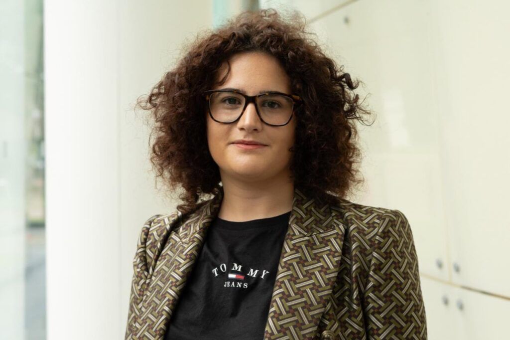 Woman with dark curly hair and glasses