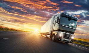 European truck vehicle on motorway with dramatic sunset light. Cargo transportation and supply theme.