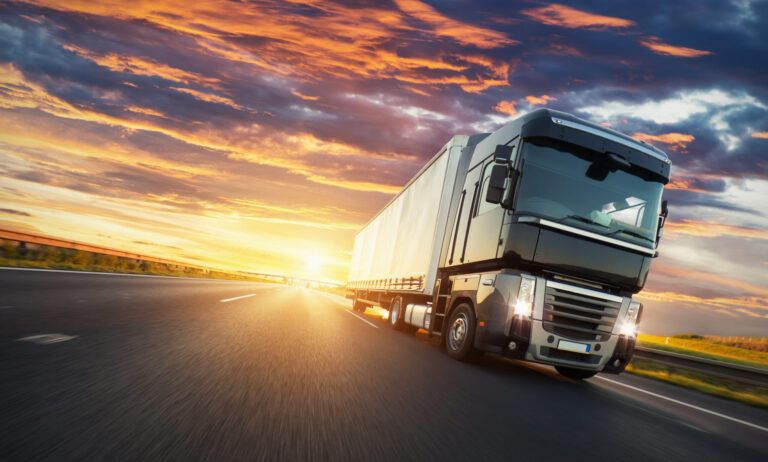 European truck vehicle on motorway with dramatic sunset light. Cargo transportation and supply theme.