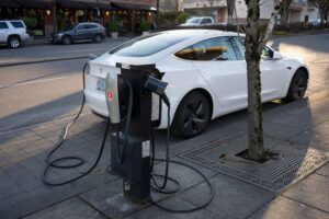 A Tesla Model 3 electric car is seen being charged at a curbside EV charging station in Lake Oswego, Oregon