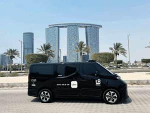 WeRide autonomous vehicle driving on a road in Al Maryah Island's Central Business District, surrounded by modern high-rise buildings and palm trees