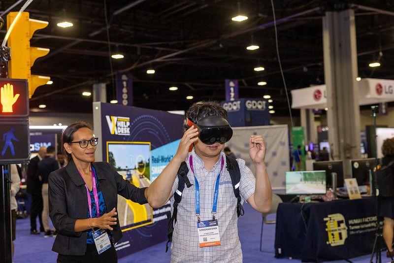 A person demonstrating how to use a piece of technology to another person at the show
