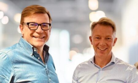 Two white men in smart shirts smiling in formal portrait with blurred background