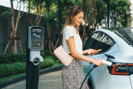UK gets 23% more public EV chargers in past year Young woman travel with EV electric car charging in green sustainable city outdoor garden in summer. Urban sustainability lifestyle by green clean rechargeable energy of electric BEV vehicle innards