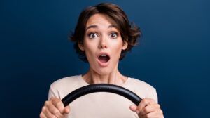 Photo portrait of lovely young lady shocked open mouth steering wheel dressed white garment isolated on dark blue color background.