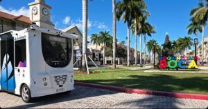 An autonomous shuttle on a bright sunny day with palm trees