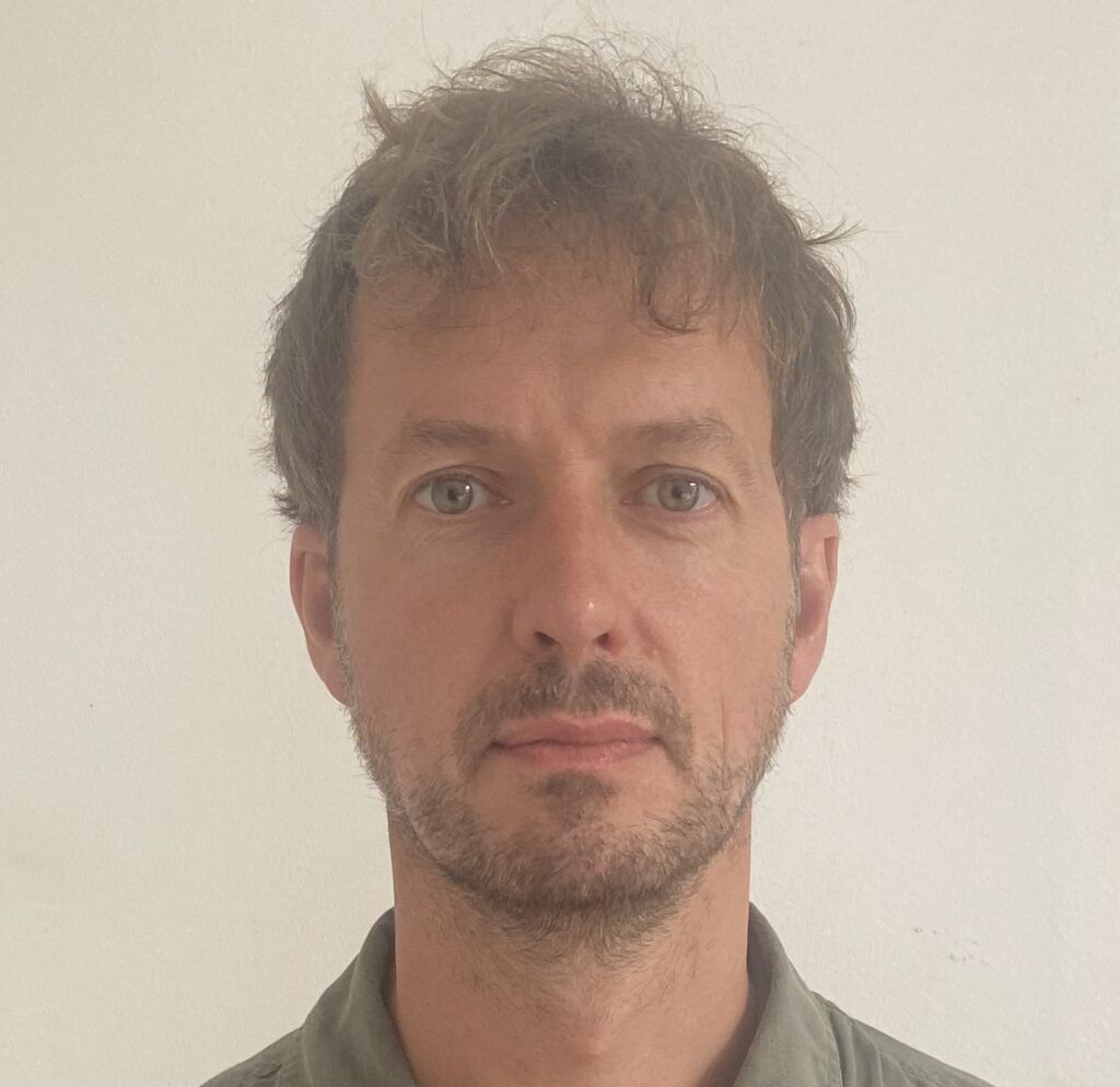 head and shoulders shot of white man with slightly untidy hair and close cropped beard