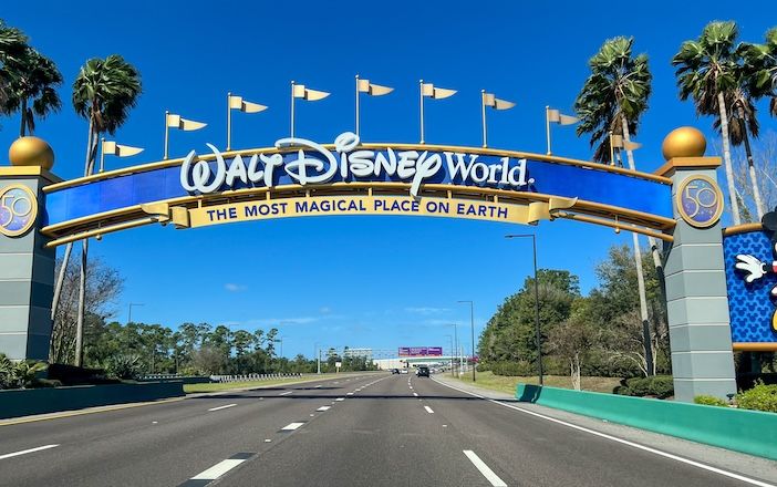 A Walt Disney World sign on a gantry above a highway