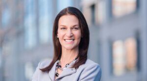 White woman with shoulder length straight brown hair in business attire