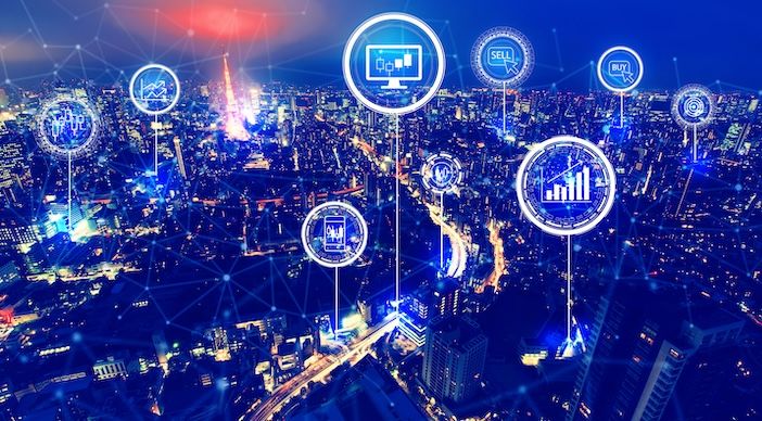 Aerial night view of a city with digital connectivity icons overlaid, representing smart city data networks and intelligent transportation infrastructure.