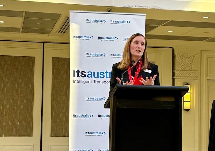 A woman speaks at a podium in front of ITS Australia branded banners at the Roads, Tolling & Tech 2026 conference in Sydney
