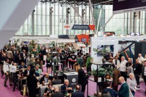 erial view of a busy exhibition hall at Intertraffic Amsterdam, with visitors networking and seated at tables in the foreground. A sign reading "You are in Hall 7 – Infrastructure" is visible, along with branding for Dow and other exhibitors, and large glass windows letting in natural light