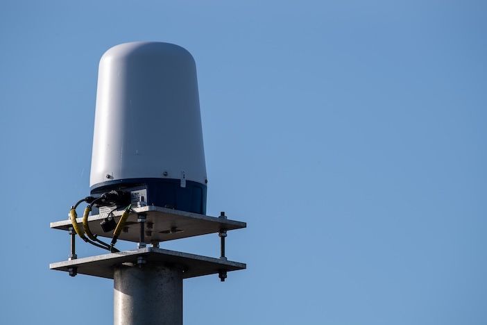 Landscape view of a Navtech 360-degree radar head and floating-plate mounting bracket against a blue sky.