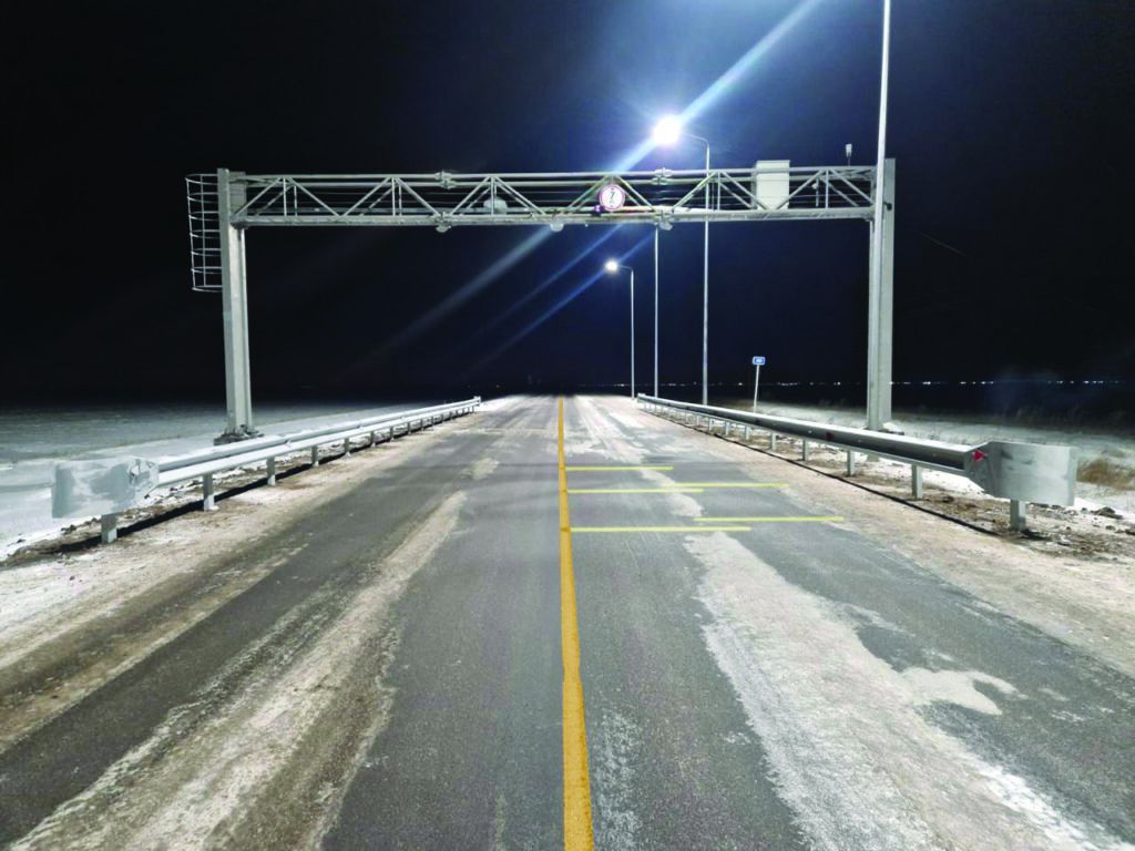 HS-WIM enforcement gantry over a snow-dusted Kazakhstan highway at night, illuminated by overhead lighting.