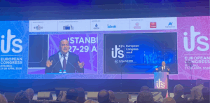 Man on stage with screens and ITS Logos