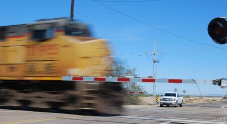 AUDIO: Research helps keep rail crossing safety on the right track Train passing through a crossing with a car in the background