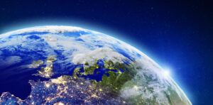 rendered view of Earth from space showing Europe and the North Atlantic at night, with city lights glowing across the continent against a dark sky
