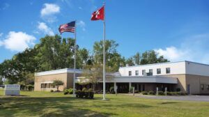 Modern low-rise Kistler office building with American and Swiss flags flying on flagpoles in front, on a sunny day