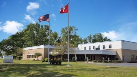 Kistler moves WIM sensor production for Build America, Buy America Modern low-rise Kistler office building with American and Swiss flags flying on flagpoles in front, on a sunny day