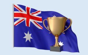 A gold trophy stands in front of a large, waving Australian flag against a pale blue background