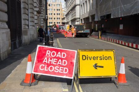 TfL expands Lane Rental scheme to more boroughs Road Ahead Closed" and "Diversion" signs on a City of London street, with contractors working in the background