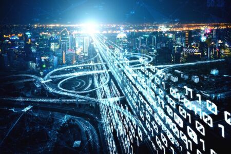The Traffic Group wins New Mexico data collection deal Aerial night-time view of a motorway interchange overlaid with glowing streams of binary code, representing digital traffic data flowing across a road network