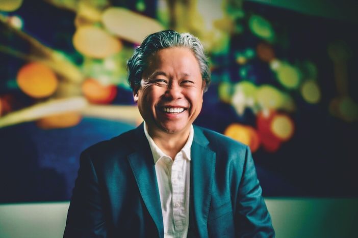 Mark Chung, IBTTA executive director and CEO, smiling in a dark teal blazer and white shirt against a blurred, colourful background