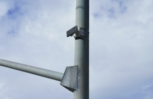 Small rectangular sensor attached to a lamppost against a partly cloudy sky