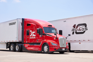 A red truck cab with "Kodiak" and "K" logos on the door, parked between two trailers, one marked
