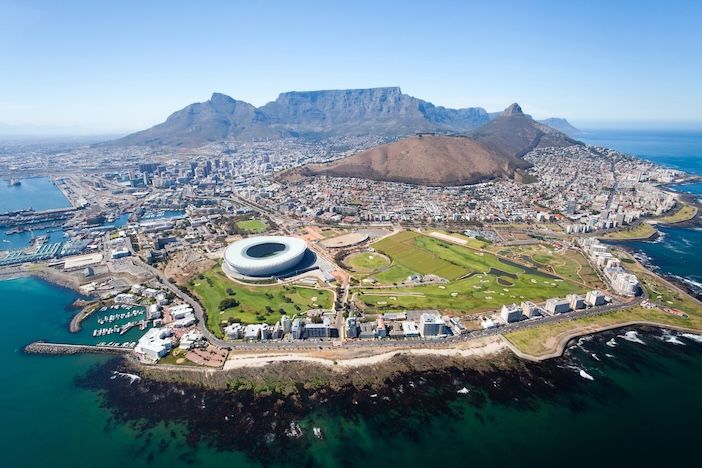 First ever ITS Africa Conference announced for 2027 in Cape Town Aerial view of a coastal city with a flat-topped mountain behind, a white oval stadium and green parkland in the foreground.