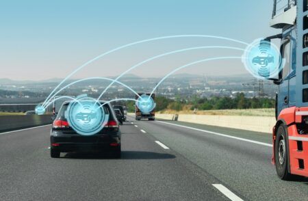 Monotch joins Data for Road Safety as provider and service creator A black car on a motorway behind a lorry, with glowing blue circles linked by curved lines above the vehicles.