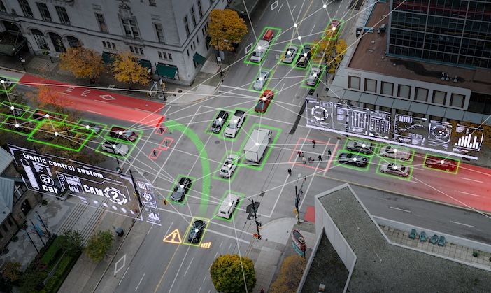 Aerial view of a city intersection with vehicles and pedestrians outlined by green and red boxes, with digital graphics overlaid.