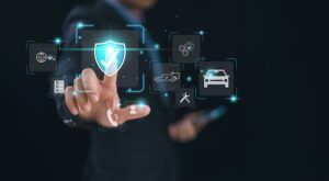 A person in a dark suit touches a glowing blue shield icon with a tick, surrounded by floating icons including a car, a tow truck, a wrench and a globe.