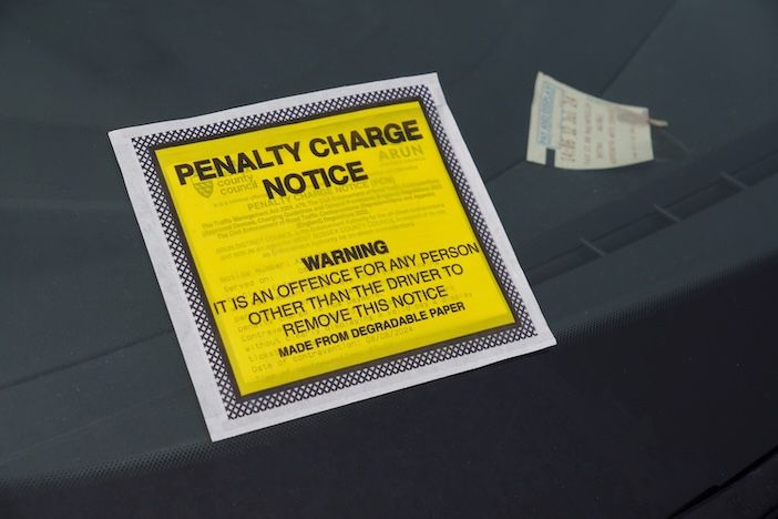 A yellow penalty charge notice stuck to the inside of a car windscreen.