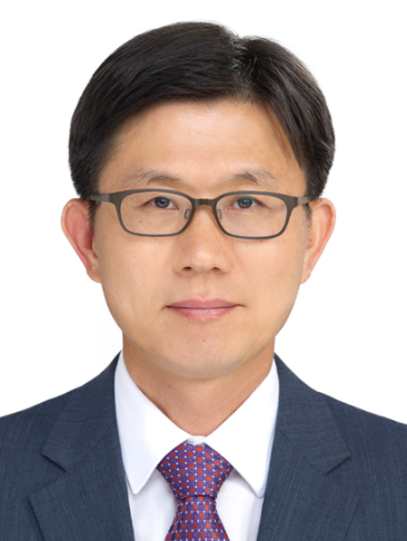 Portrait of JongKi Lee, a man with short dark hair and glasses, wearing a navy suit, white shirt and purple patterned tie